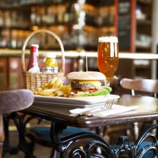 En hamburgare med pommes frites och en öl serverat på ett bord på The Bishops Arms.