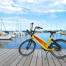Bilden visar en gul DigiBike som står på en brygga med Mälaren och båtar i bakgrunden. Bilden visar en gul DigiBike som står på en brygga med Mälaren och båtar i bakgrunden.