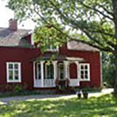 Bilden visar en röd träbyggnad med vita knutar på Finnsta Gård. Bilden visar en röd träbyggnad med vita knutar på Finnsta Gård.