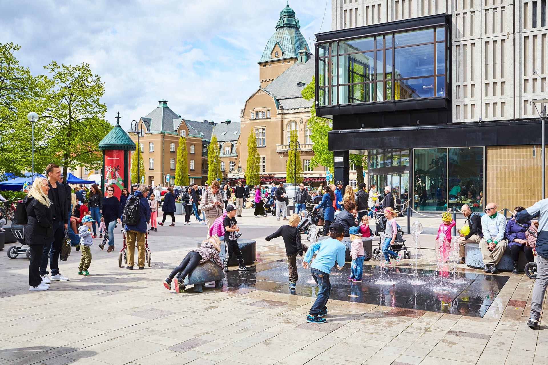 Folksamling i Västerås City. Barn som leker i vattenfontän med Stora Torget i bakgrunden. Fotograf: Pia Nordlander