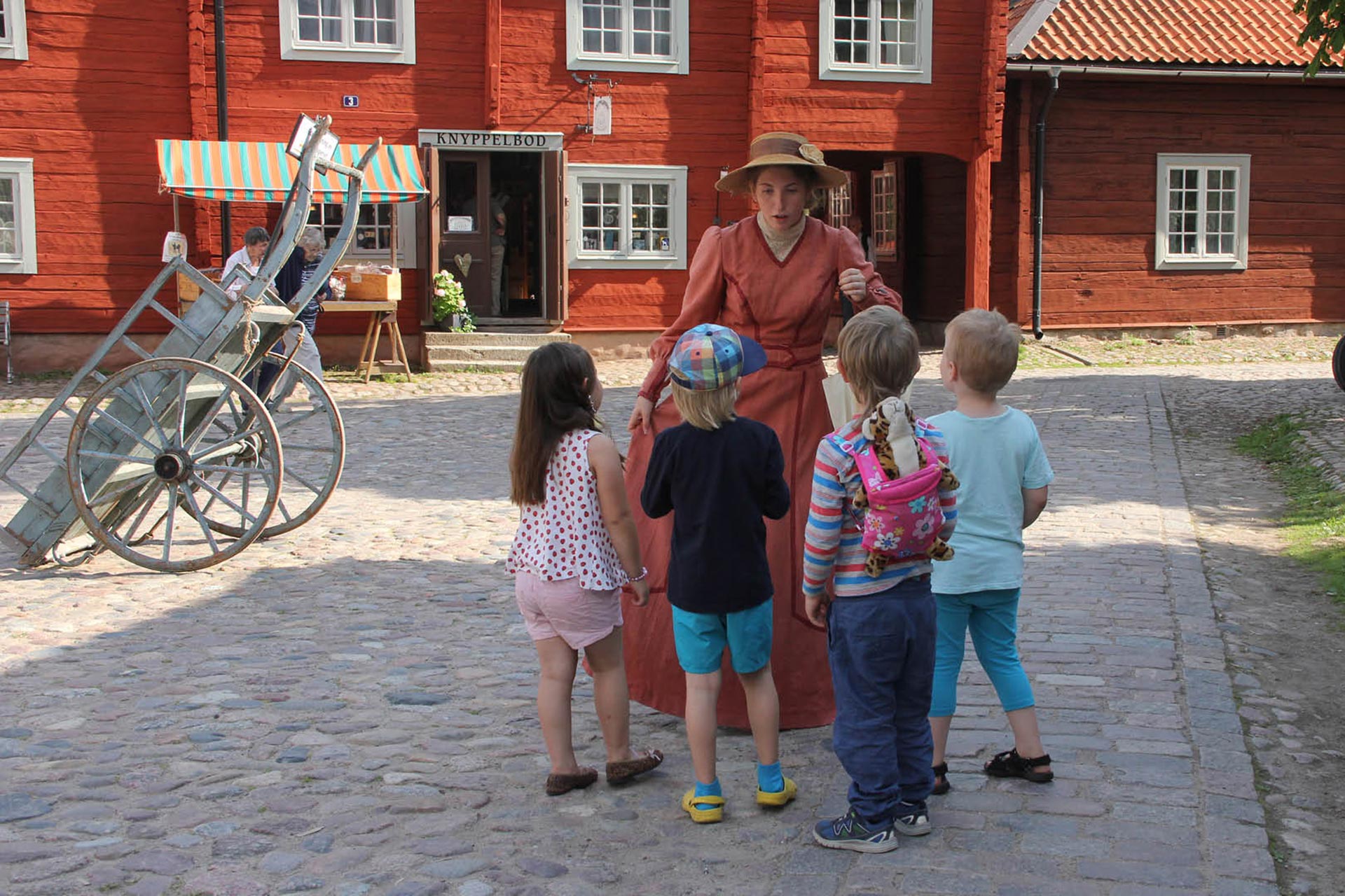 En kvinna hade kläder från förr och barn i ring framför henne. En kvinna hade kläder från förr och barn i ring framför henne.