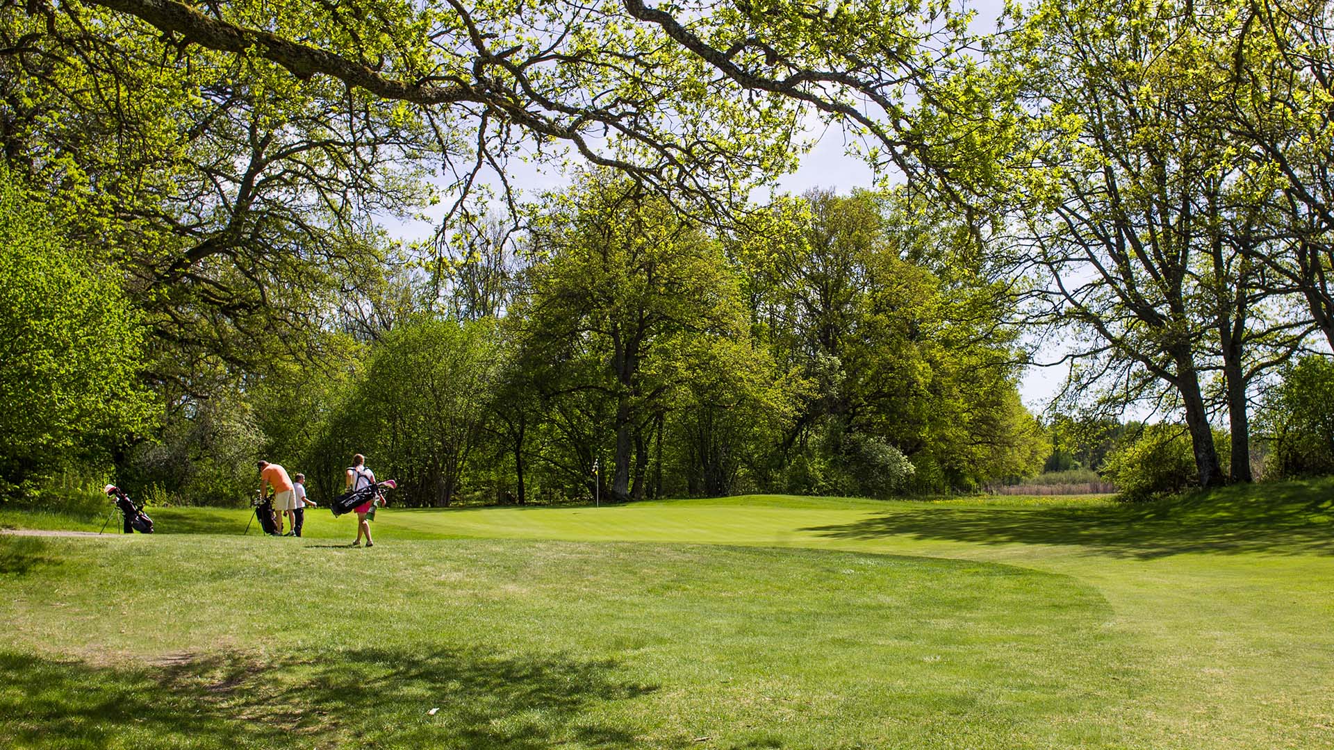 Vy över en glänta på golfbanan, två personer står en bit bort med sina golfbägar. Pressbild