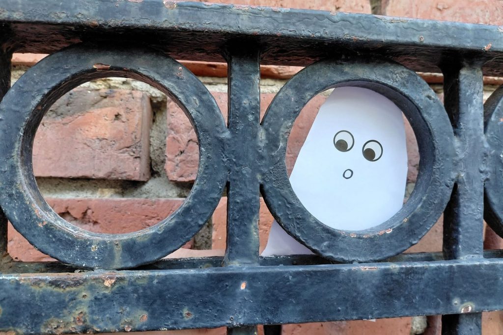 Ett spöke som tittar fram genom ett gjutjärnsstaket.