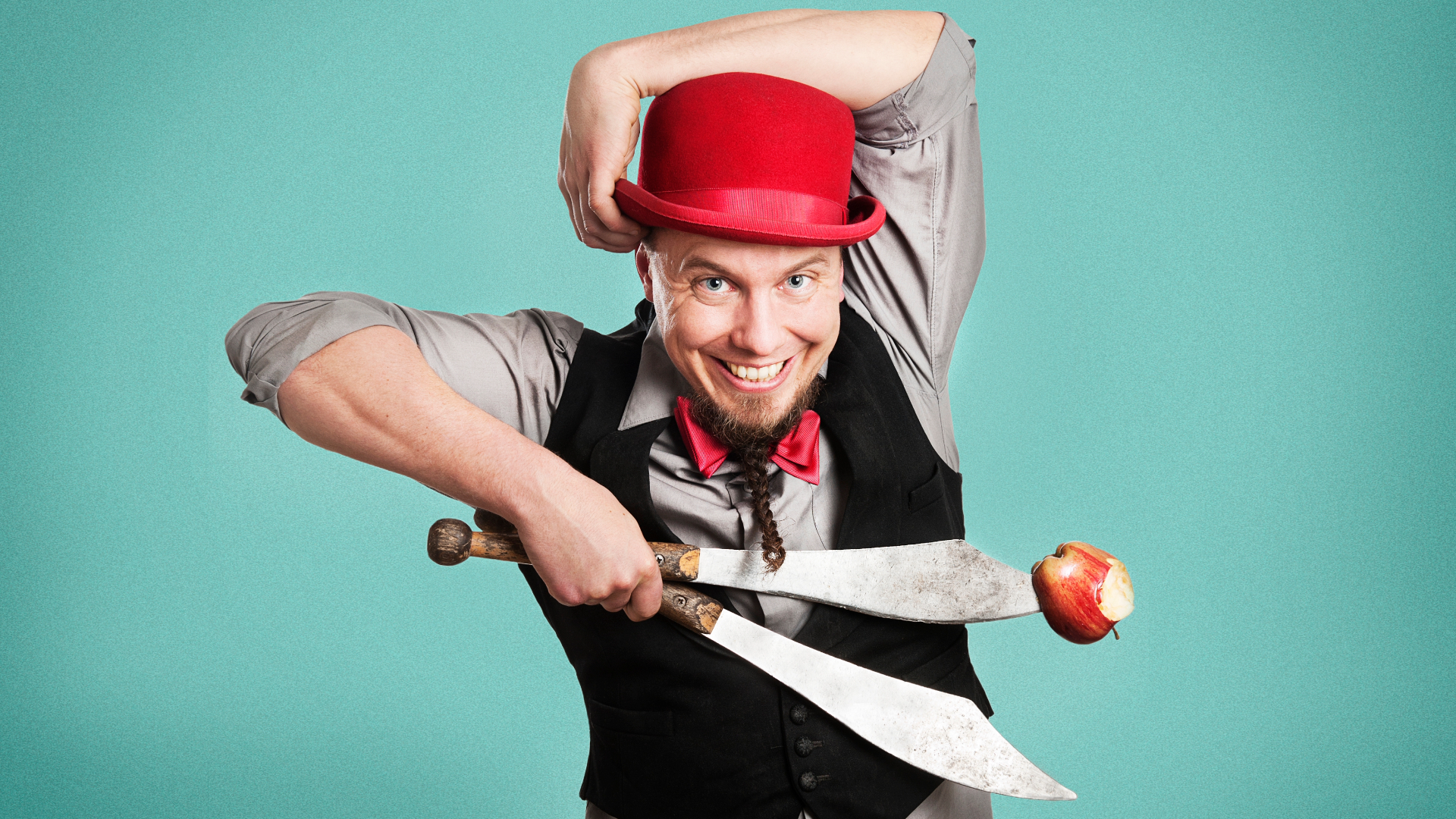 En gycklare spexar inför bild med äpple och knivar och en röd hatt.