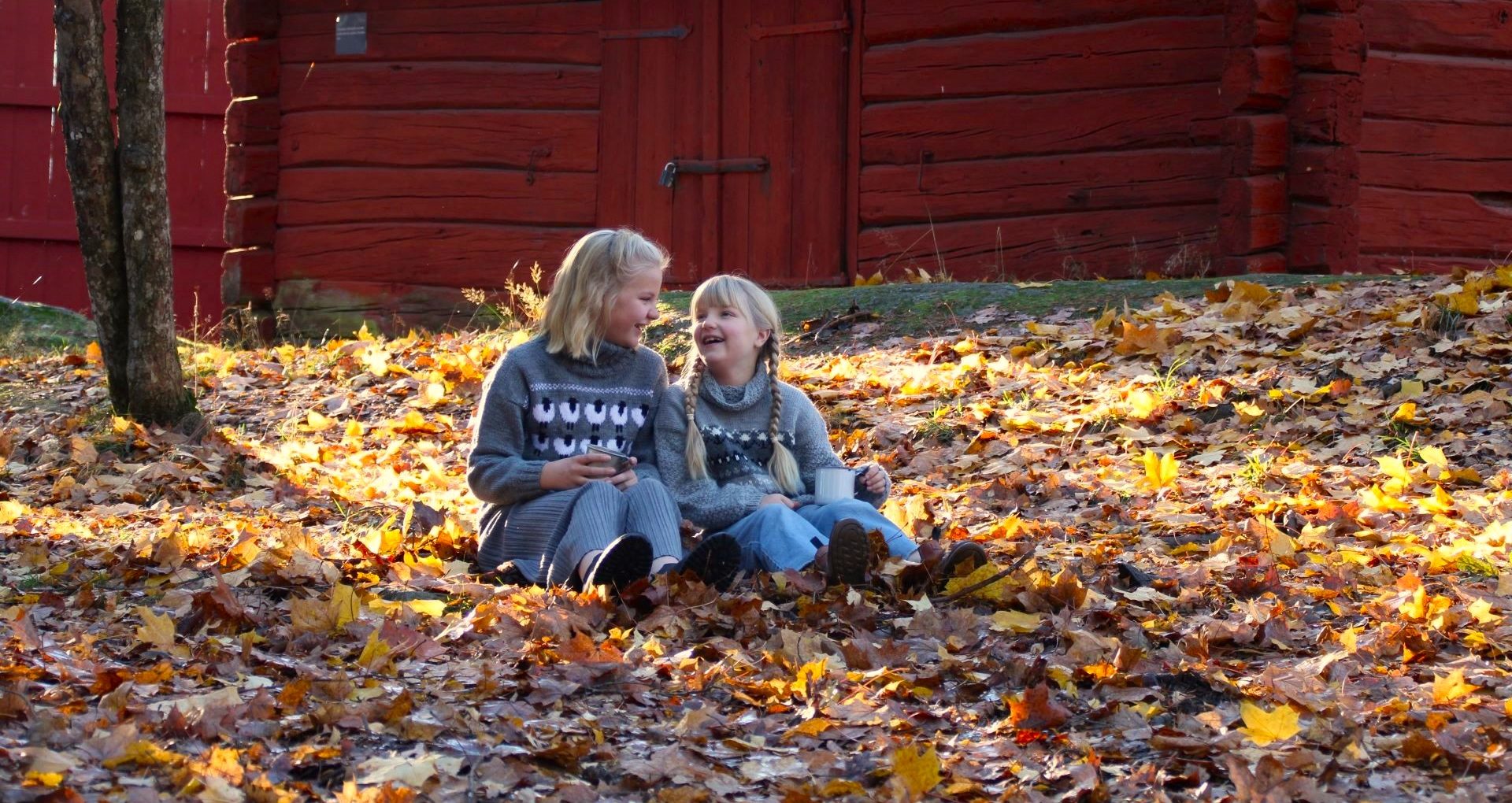 Två barn sitter bland höstlöven.