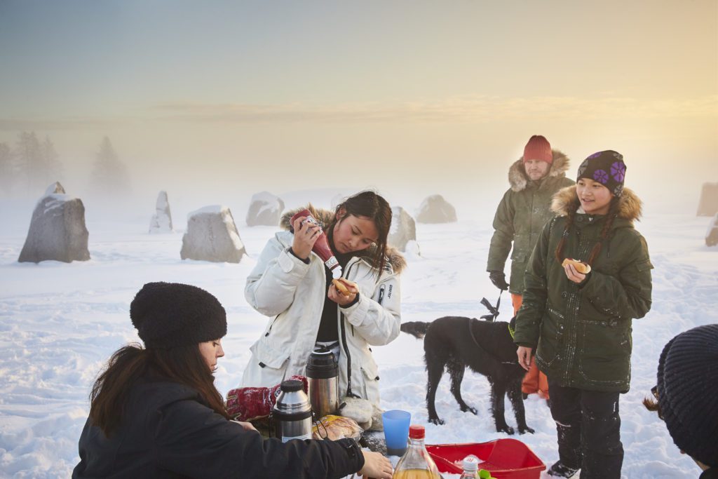 Människor som har grillat korv och äter i snön