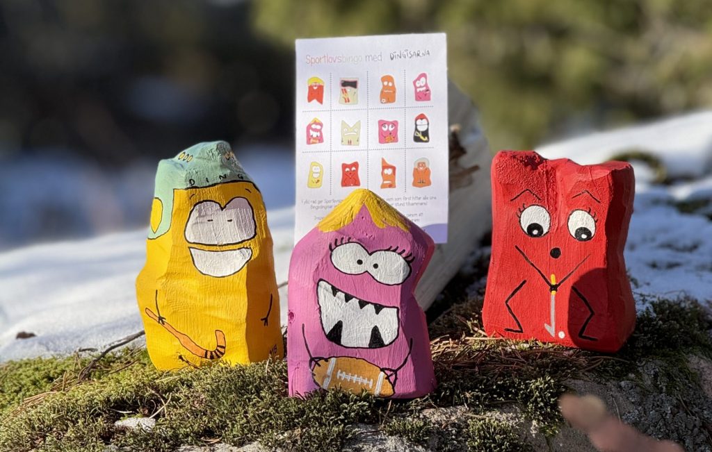 Färgglada stenfigurer på en stubbe i skogen.