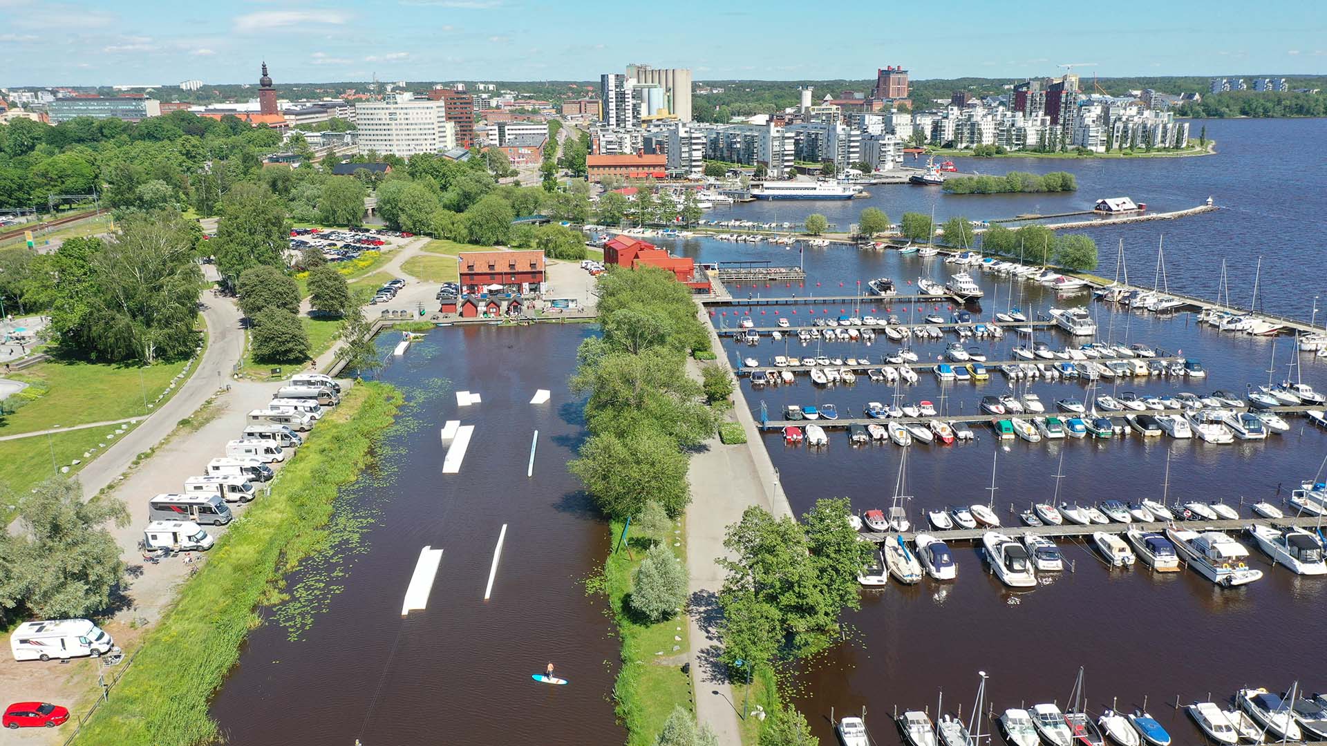 Drönarvy över Västerås gästhamn med båtar, husbilar samt byggnader i bakgrunden. Foto Avig Photo