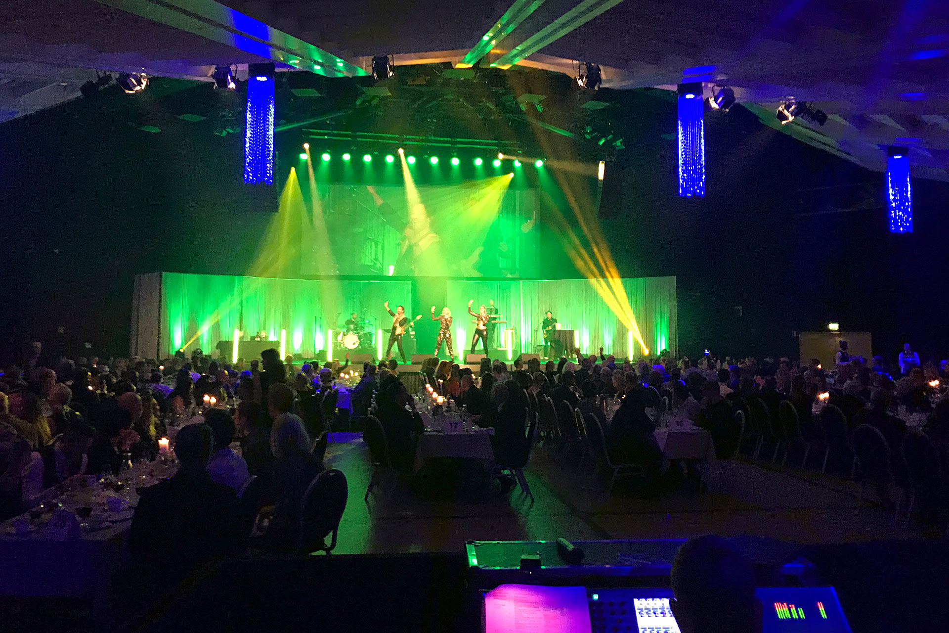 Ett band spelar på scen i grönt sken med ett gungande publikhav framför. Pressbild.