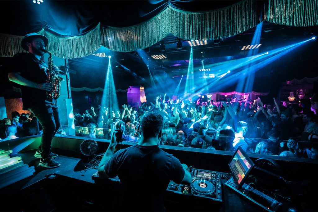 DJ och saxofonist blickar ut över dansgolvet på nattklubben Publik i Västerås