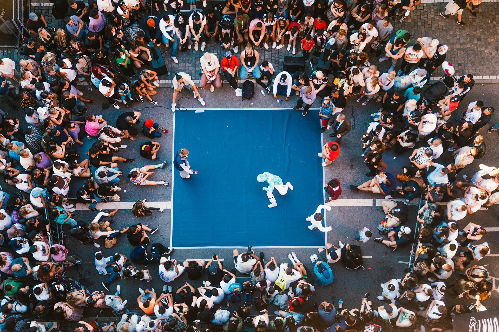 Drönarvy över publik och en dansmatt där killar dansar breakdance. Foto: Avig Kazanjian