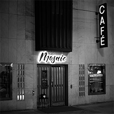 Ingången till Café Mosaic. En dörr med neonskylt "Mosaic" ovanför.