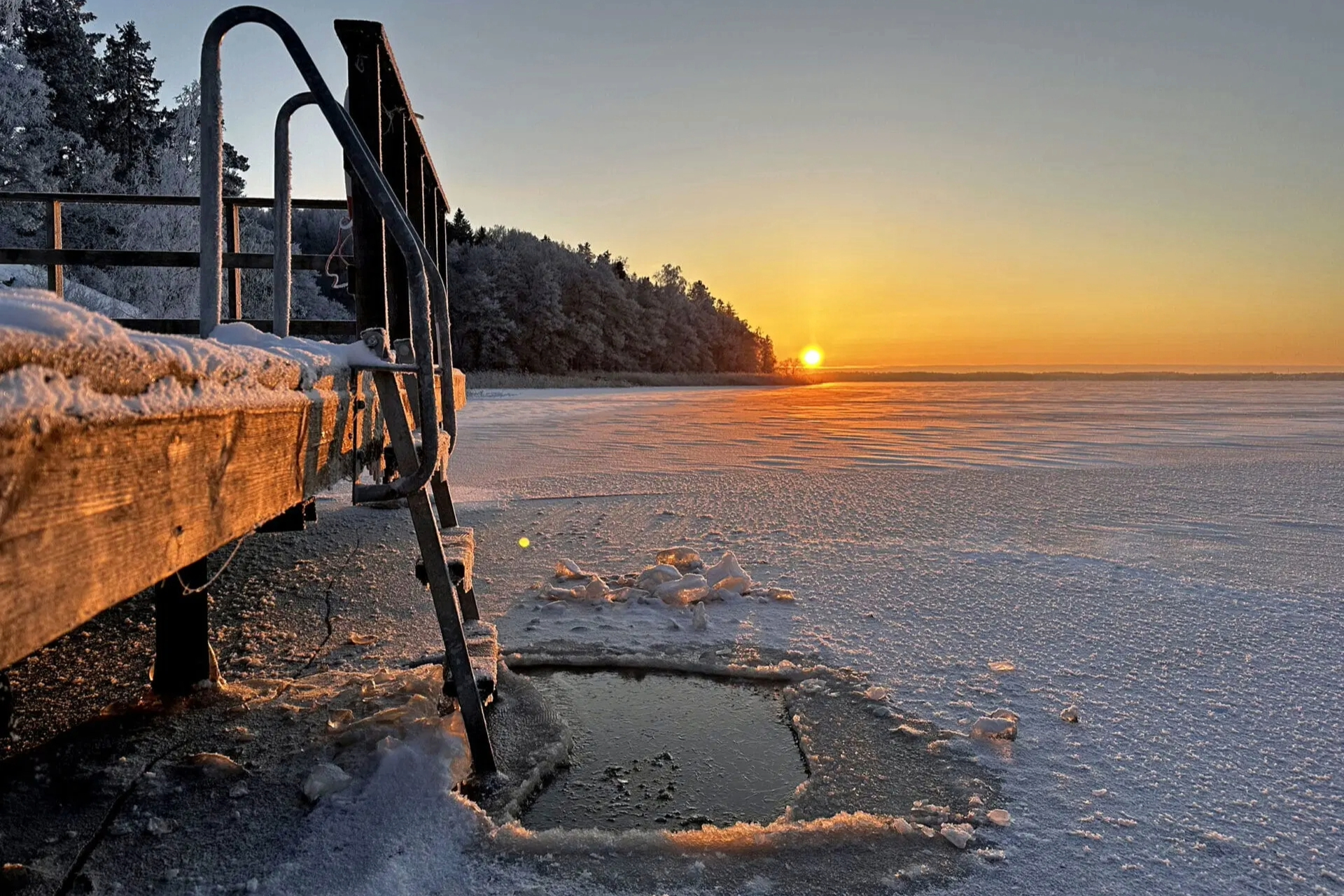 En vacker solnedgång från en brygga ned stege ned u en isvak,. Pressbild: Aktivt uteliv