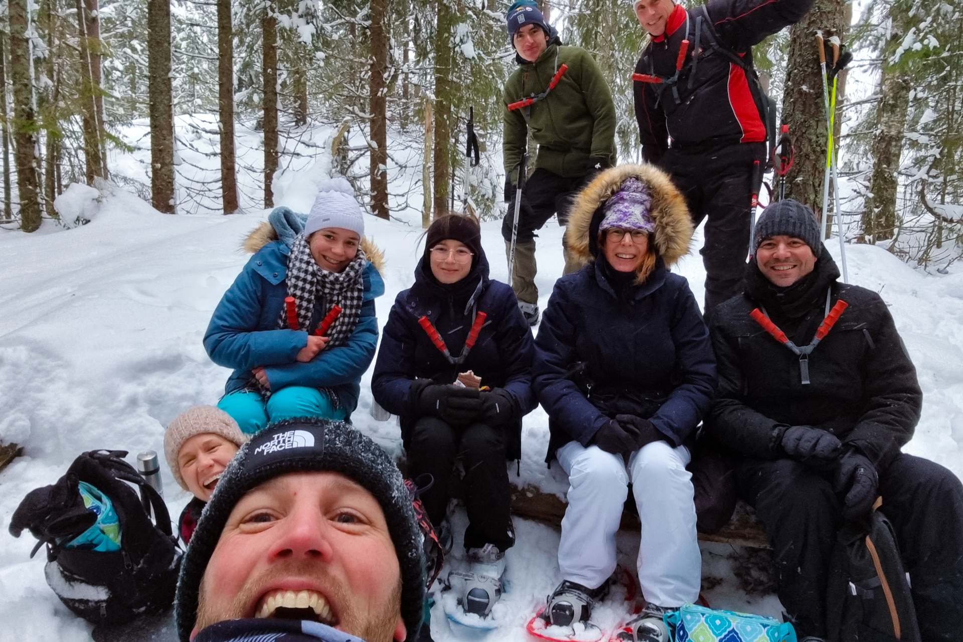 Ett gäng sitter på ett träd och ser glada ut inför fotografering med snöskor. Fotograf: Nordic Discovery