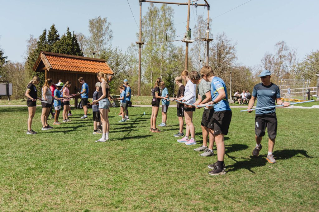 Två grupper människor samarbetar i en teambuilding-aktivitet på en gräsplan