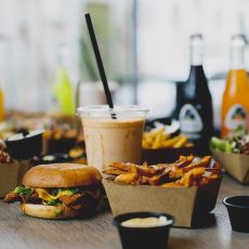 Uppdukat bord med hamburgare, pommes, dipp, en shake och två läskflaskor.