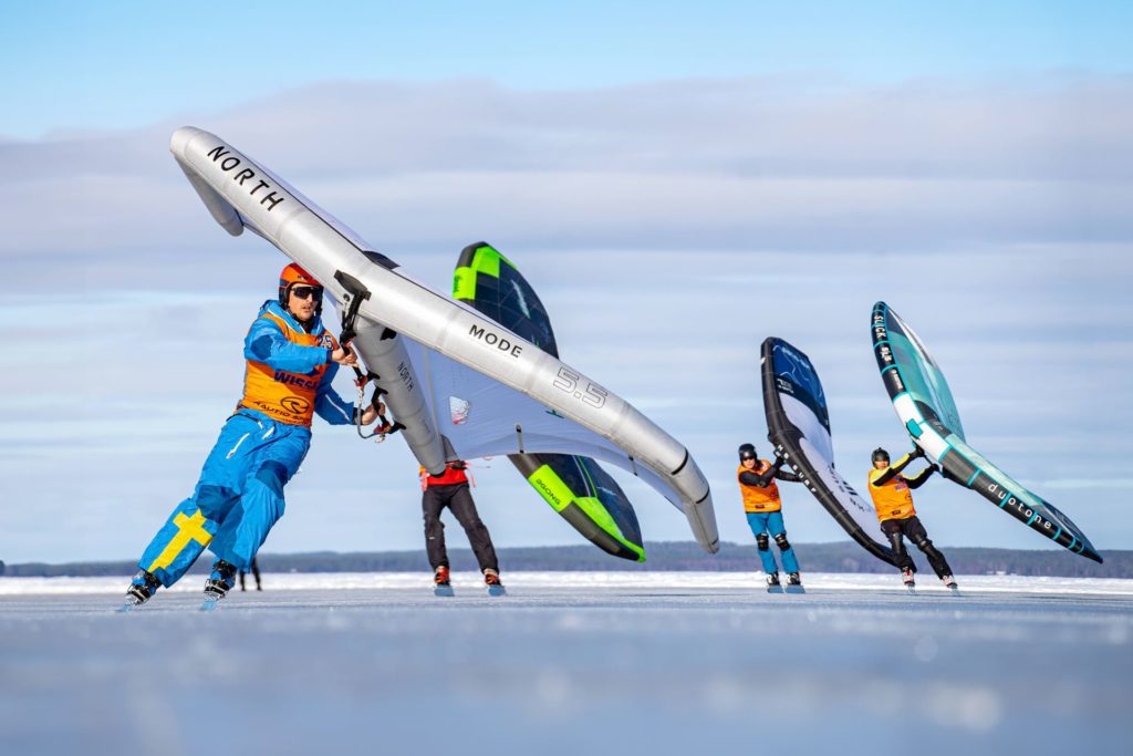 Personer i färgglada kläder som isseglar på isen