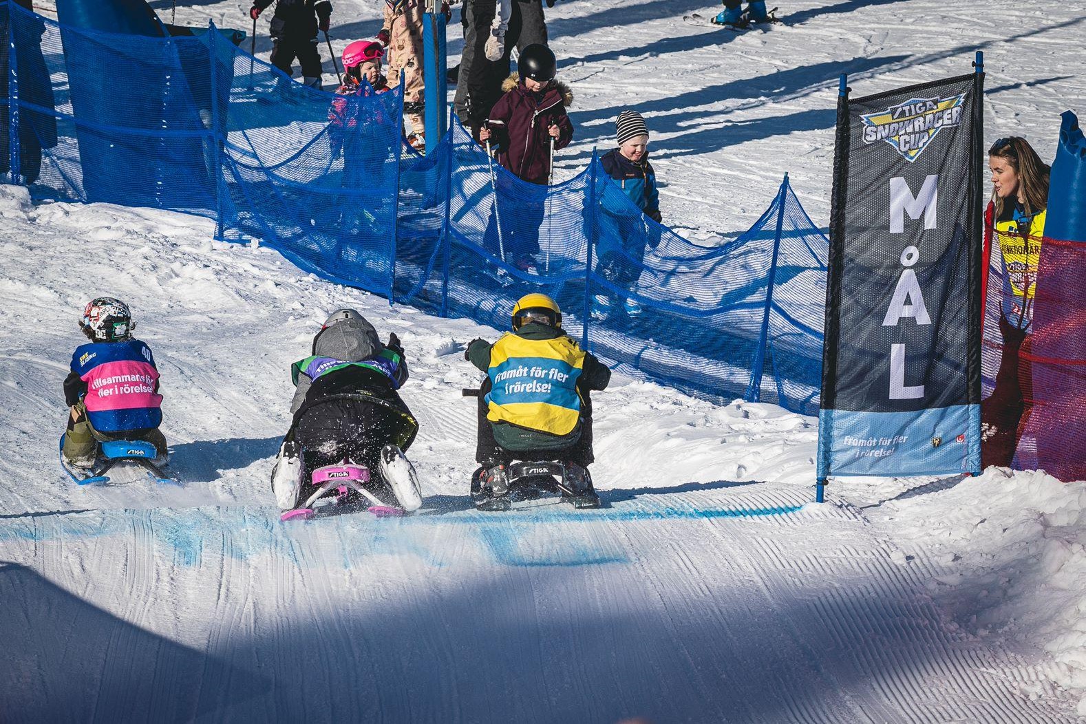 Tre personer som åker snowracer i en snöig backe
