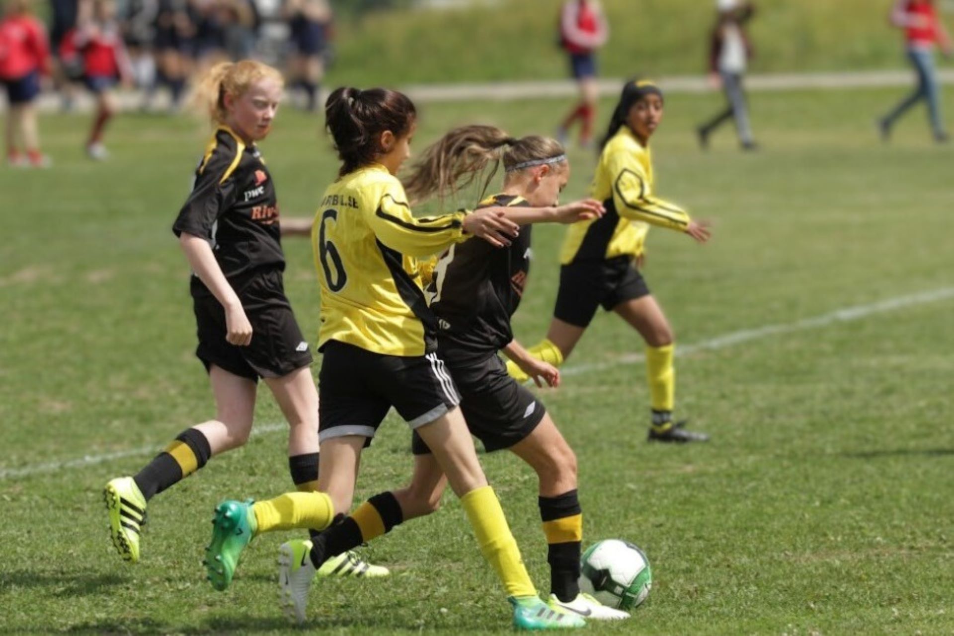 Fyra ungdomar som spelar fotboll på en gräsplan.