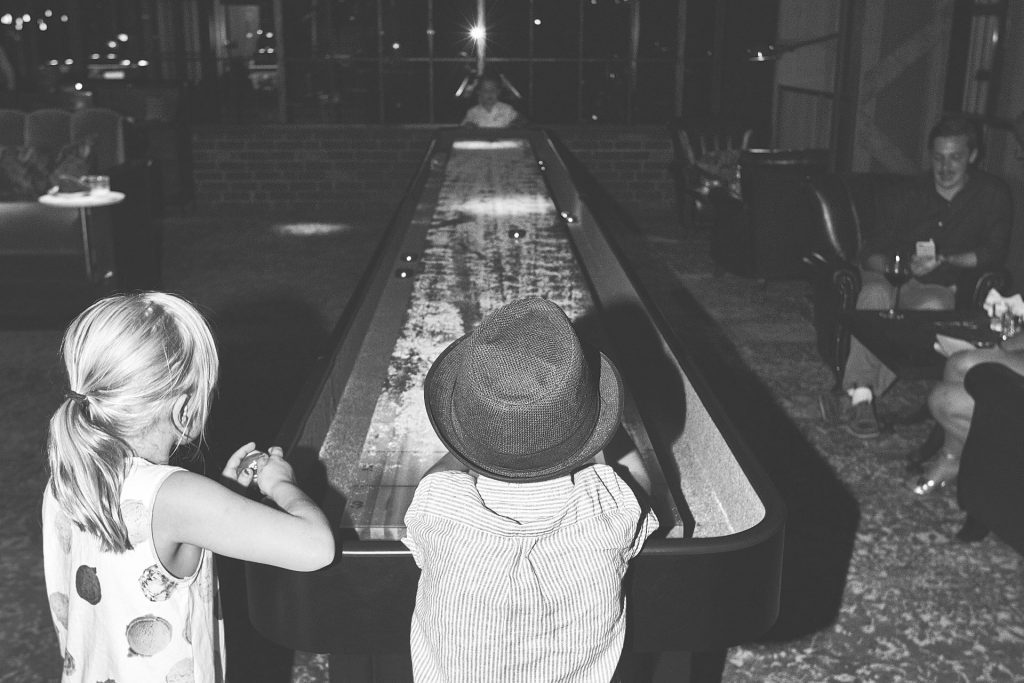 Tre barn som spelar shuffleboard på The Playground inne i The Steam Hotel.