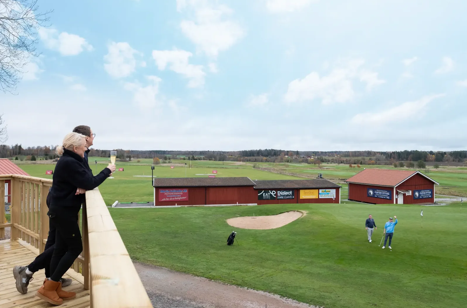 Två personer står på en altan och tittar ner över en golfgreen på Skerike GK
